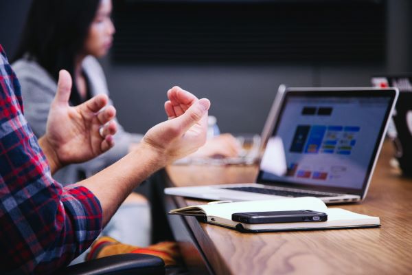 Explaining with hands in front of a computer and a notebook